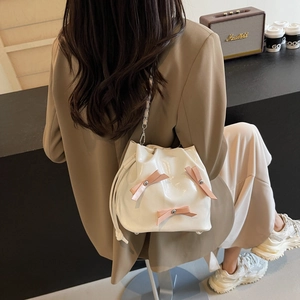 Sac seau blanc avec nœuds roses et bandoulière chaîne dans une scène de style de vie