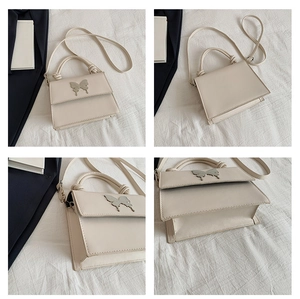Gros plan du sac en cuir crème avec fermoir papillon argenté et détails de texture fine