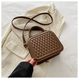 Detailed view of coffee brown quilted square bag with gold hardware on blazer