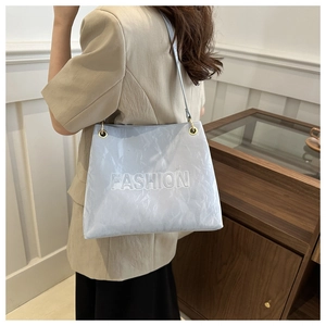 Detail of light blue tote bag with FASHION embossed texture and thin shoulder strap