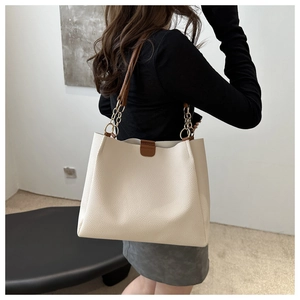 Dettaglio borsa tote in pelle crema con tracolla a catena oro e fibbie marroni