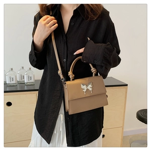 Détail du sac carré kaki avec fermoir papillon argenté et poignée nouée élégante
