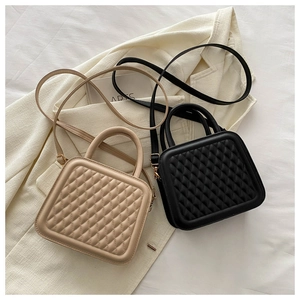 Detail of quilted square handbags in beige and black displayed on a cream blazer
