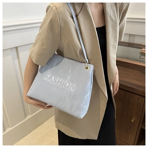 Detail of light blue tote bag showing fashion embossed letters and golden hardware
