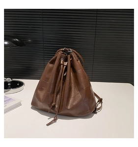 Detail of a brown PU leather bucket bag with geometric stitching and drawstring closure