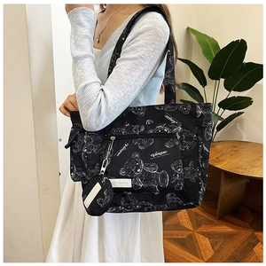 Detail of a black canvas tote bag featuring white bear prints and a side pocket