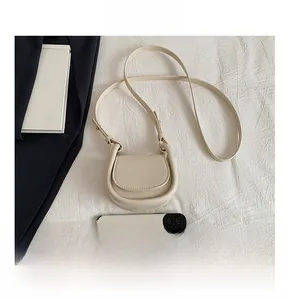 Detailed view of beige mini saddle bag showing compact size compared to a smartphone