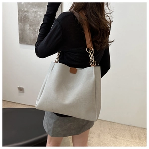 Detail of light grey lychee texture tote bag with brown leather and gold chain strap