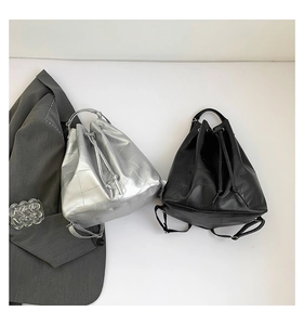 Detail of silver and black drawstring bucket backpacks with a textured patchwork design