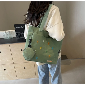 Détail du cabas en toile verte avec broderie de lettres colorées et mini pochette