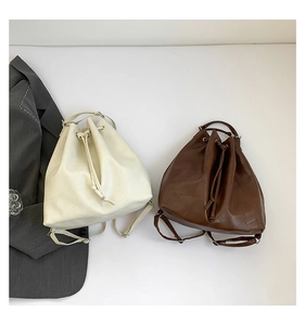 Flat lay of cream and dark brown drawstring bucket bags with geometric quilting details