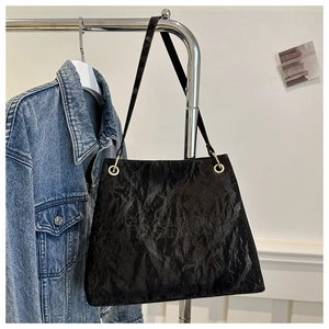 Detailed view of black wrinkled leather tote bag with embossed Fashion logo and metal ring