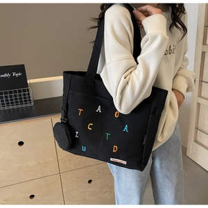 Détail du sac cabas en toile noire avec broderie colorée et pendentif porte-monnaie rond