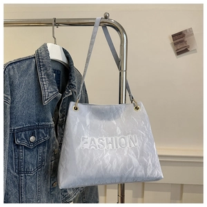 Detail of grey tote bag with pleated texture and white FASHION lettering in relief