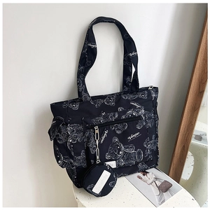 Detail of black tote bag featuring white bear prints and matching round coin purse charm