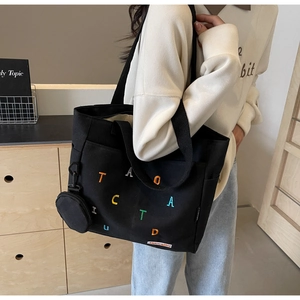 Détail d'un sac cabas en toile noire avec broderie colorée et mini pochette ronde