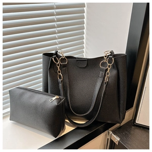 Dettagli della borsa tote nera con texture a grana, tracolla a catena dorata e pochette interna