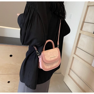 Detail showing pink textured leather saddle bag with gold metal trim and top handle