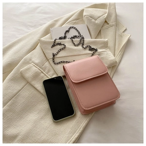 Close-up of pink leather mobile phone bag with black chain on beige suit jacket