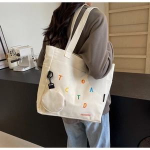Détail du sac cabas en toile avec broderie de lettres colorées et petit porte-monnaie