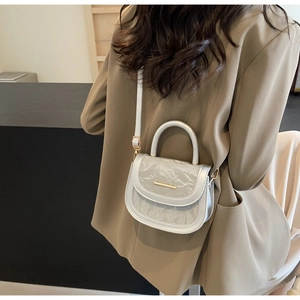 Detail of minimalist saddle bag with marble print flap and golden metal hardware