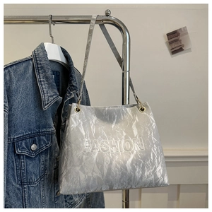Detail of silver tote bag with textured crinkle finish and embossed Fashion lettering