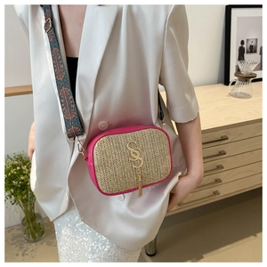Detail of woven straw crossbody bag with pink leather trim and ethnic style wide strap