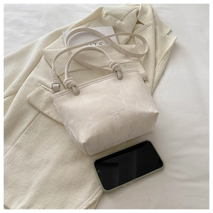 Détail du sac beige avec poignée à nœud en cuir et texture marbrée élégante