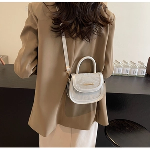 Detail of silver saddle bag with metallic texture, gold buckle and thin shoulder strap