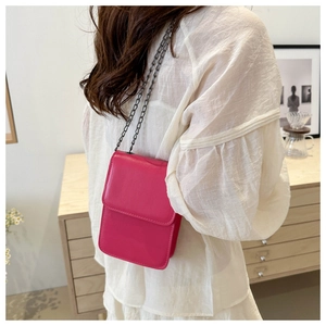 Chic rose red mobile phone crossbody bag with grey metal chain strap worn by a model