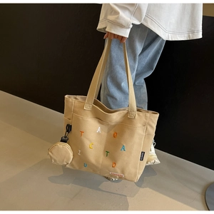 Détail du cabas en toile kaki avec broderie colorée et petite pochette ronde attachée