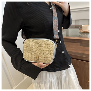 Detail of woven straw bag featuring gold letter hardware and ethnic print wide strap
