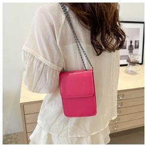 Rear view of a model wearing a hot pink leather mini phone bag with a grey metal chain strap