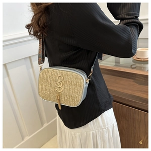 Detailed macro of SSS gold logo and metal tassel on beige woven straw handbag