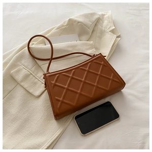 Detail of brown quilted shoulder bag with smartphone to show interior storage capacity