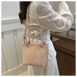 Détail du sac à main rose texturé avec poignée nouée et anneaux métalliques