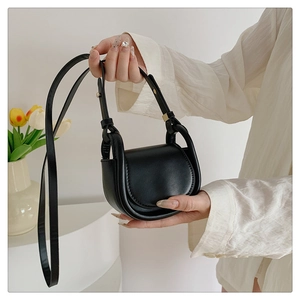 Detail view of a black mini flap handbag with matte finish and elegant top handle strap