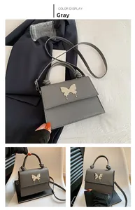 Détails du sac à bandoulière gris avec boucle papillon dorée et poignée ronde