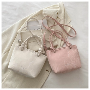 Détail de sacs à main crème et rose en similicuir avec texture froncée et deux poignées