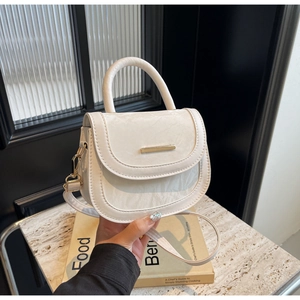 Detail of cream saddle bag with pleated leather texture and gold metal clasp