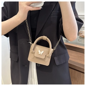 Close-up of khaki mini handbag with white butterfly accent and golden chain strap detail