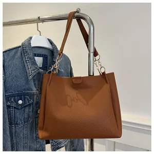 Dettaglio della borsa tote in pelle marrone con catena dorata su una gruccia