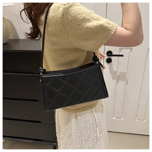 Detail of black quilted shoulder bag with gold hardware and stylish knotted strap