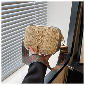 Detail of woven straw bag with gold SS logo, fringe tassel and ethnic printed wide strap