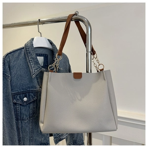 Dettaglio borsa tote in pelle litchi bianca con manici marroni e catene dorate