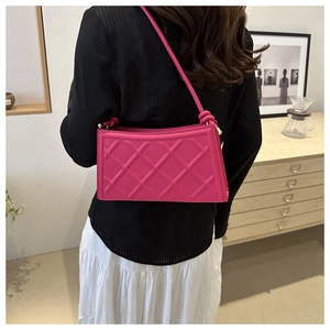Detail view of fuchsia quilted shoulder bag with knot strap against a minimalist interior