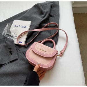 Detailed view of pink saddle bag with marble texture and metallic accents on gray blazer