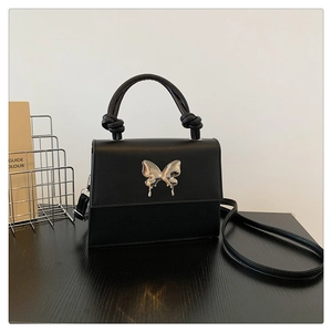 Détail du mini sac bandoulière noir avec fermoir papillon argenté et poignée nouée