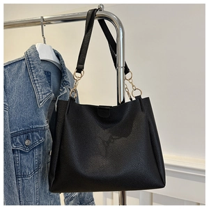 Dettaglio della borsa tote in pelle nera con elegante catena in metallo dorato