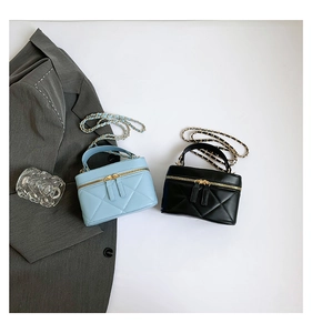 Detail of quilted vanity bags with gold dual zippers and leather chain strap in blue and black